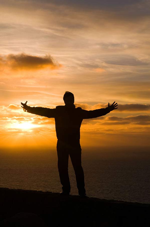 Man silhouette with open hands during sunset