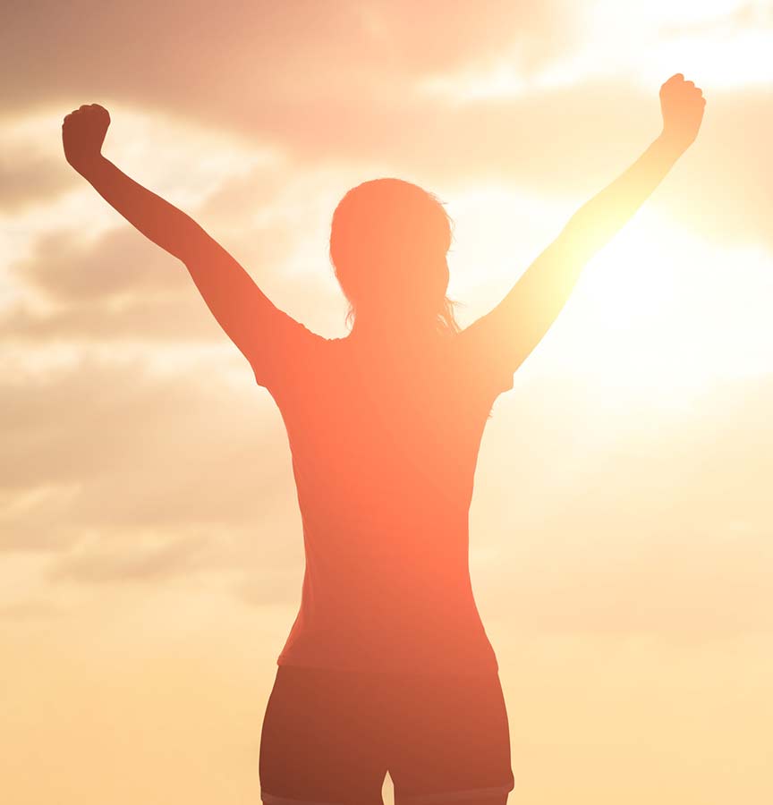 Triumphant person facing sun